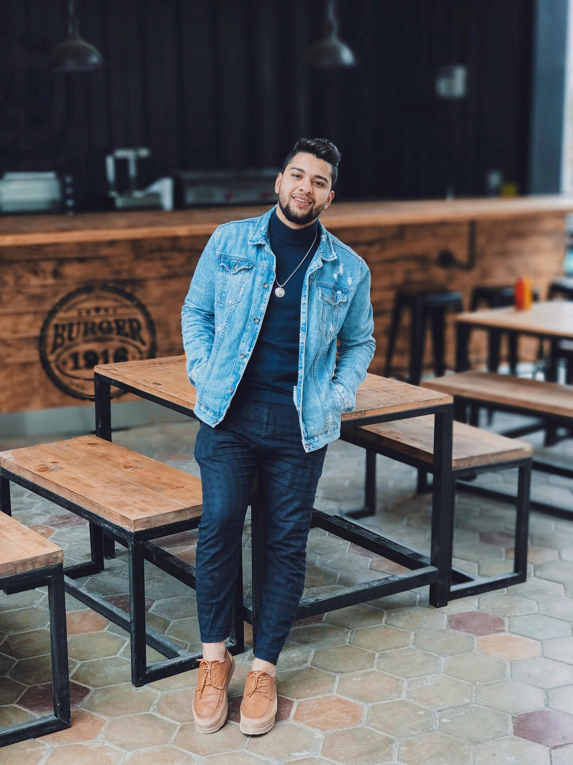 Casual young man posing in a modern urban restaurant setting.